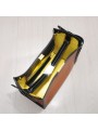 Bolso de mano de cuero perforado bicolor marrón, cierre de giro en metal dorado y correa de grosgrain con mosquetones.