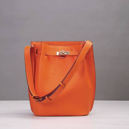 Borsa secchiello in pelle martellata arancione con cinturini e lucchetto, finiture dorate e tracolla in pelle regolabile.