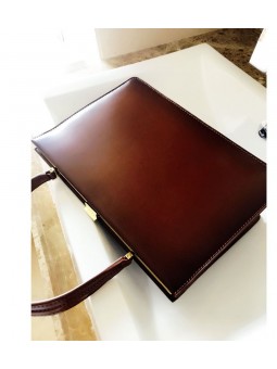 Borsa in pelle marrone con struttura dorata e clip. Due scomparti e una tasca con zip.