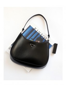 Black leather hobo bag featuring a metal triangle on the front, rounded lines, and a curved top.